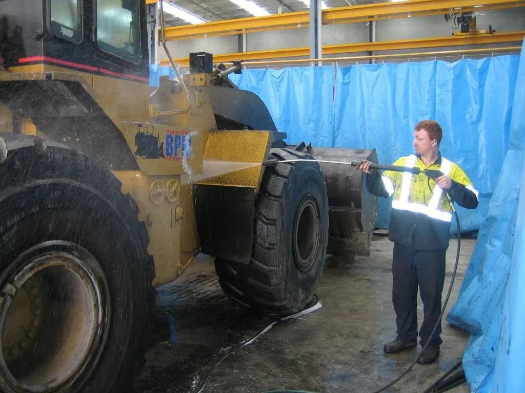 Buckley's mechanic pressure-washing a wheel loader in the workshop
